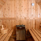Interior view of wooden sauna with two benches on either side, Harvia heater with stones in center, wooden bucket with ladle 