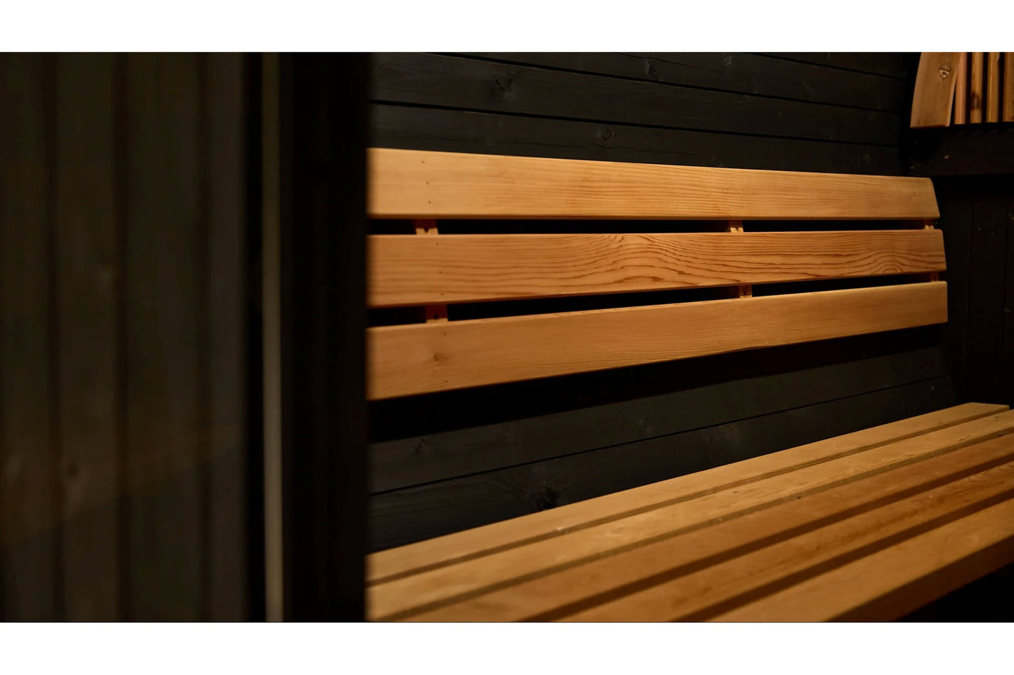 Wood and black barrel sauna interior showing horizontal wood slats and bench seating detail