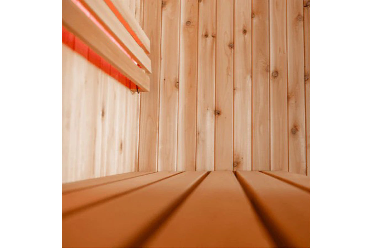 Interior view of wooden sauna with light wood paneling and red towel on upper shelf