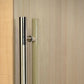 Stainless steel cylindrical door handle on light wood sauna door frame with frosted glass panel