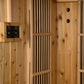 Natural wood sauna interior with vertical cedar slats, digital control panel with green buttons on left wall, and ventilation