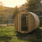 Wooden barrel sauna with rounded cylindrical design and dark glass door, positioned in backyard setting with residential buil