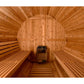 Interior view of wooden barrel sauna with cedar benches on both sides and black heater stove in center
