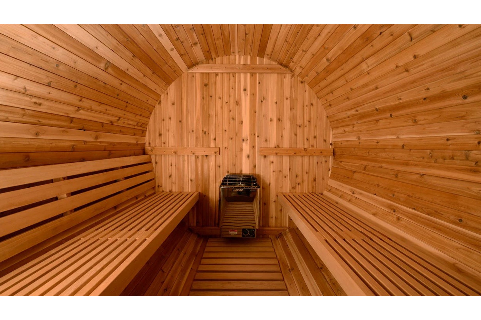 Interior view of wooden barrel sauna with cedar benches on both sides and black heater stove in center
