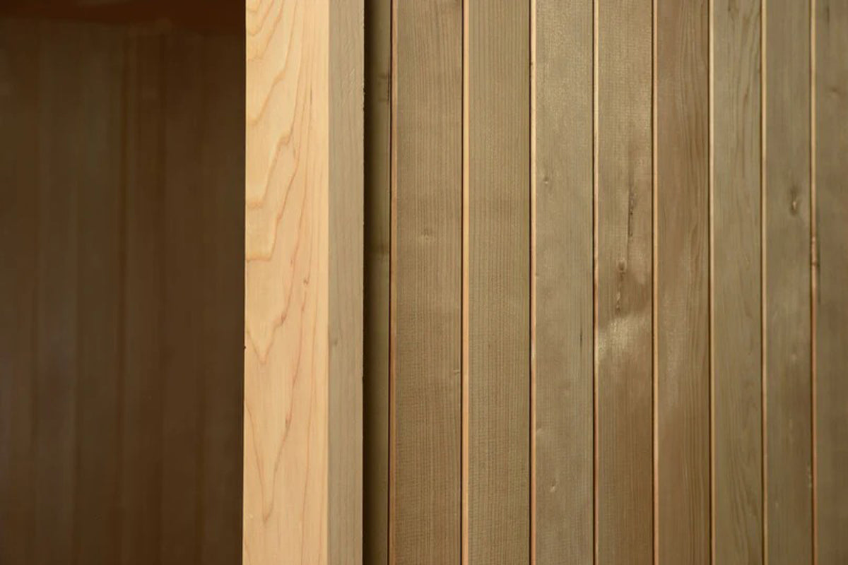 Almost Heaven Spectacle 2-person indoor sauna with light and dark wood paneling, showing hybrid wood construction on white ba