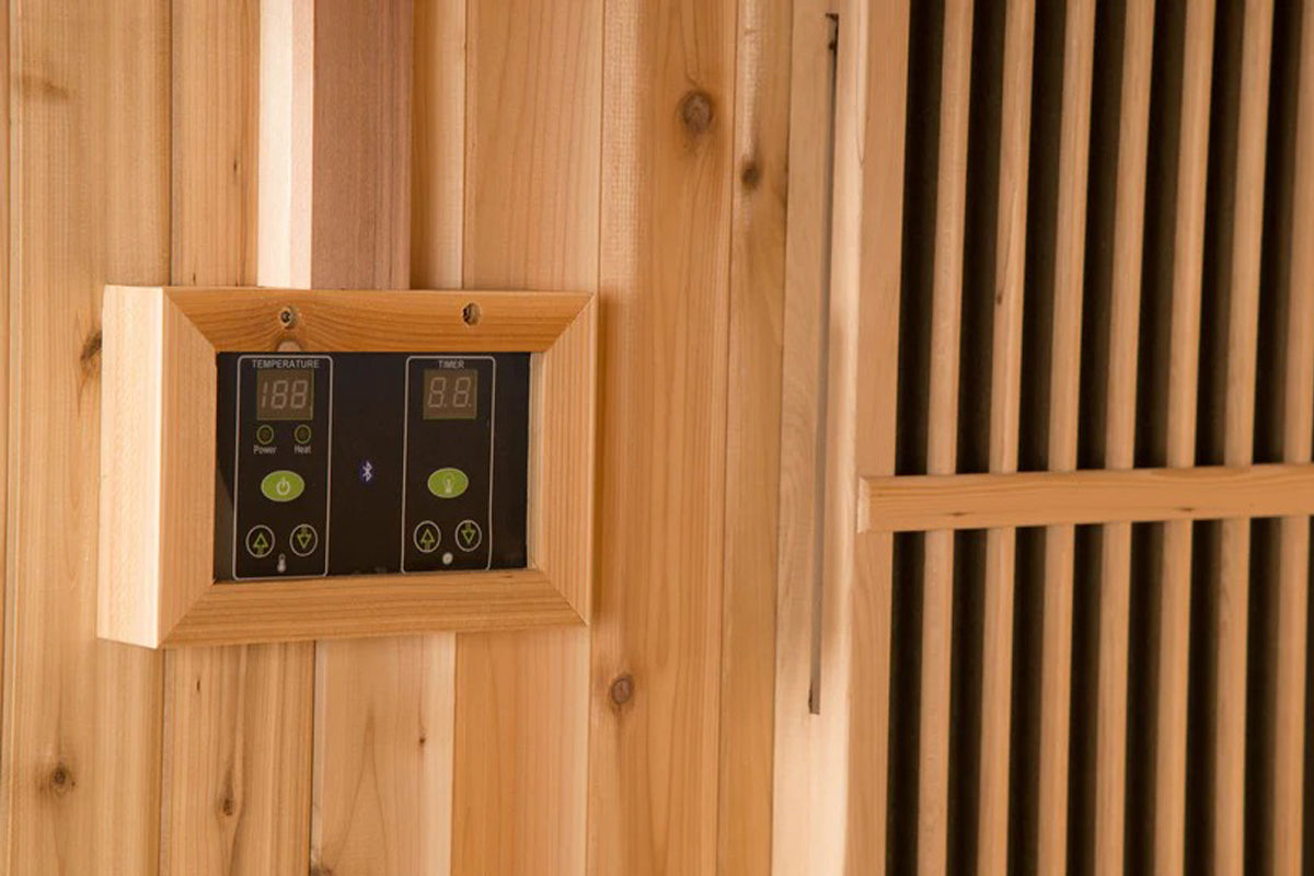 Dual digital control panels with temperature displays mounted in wooden frame on sauna wall