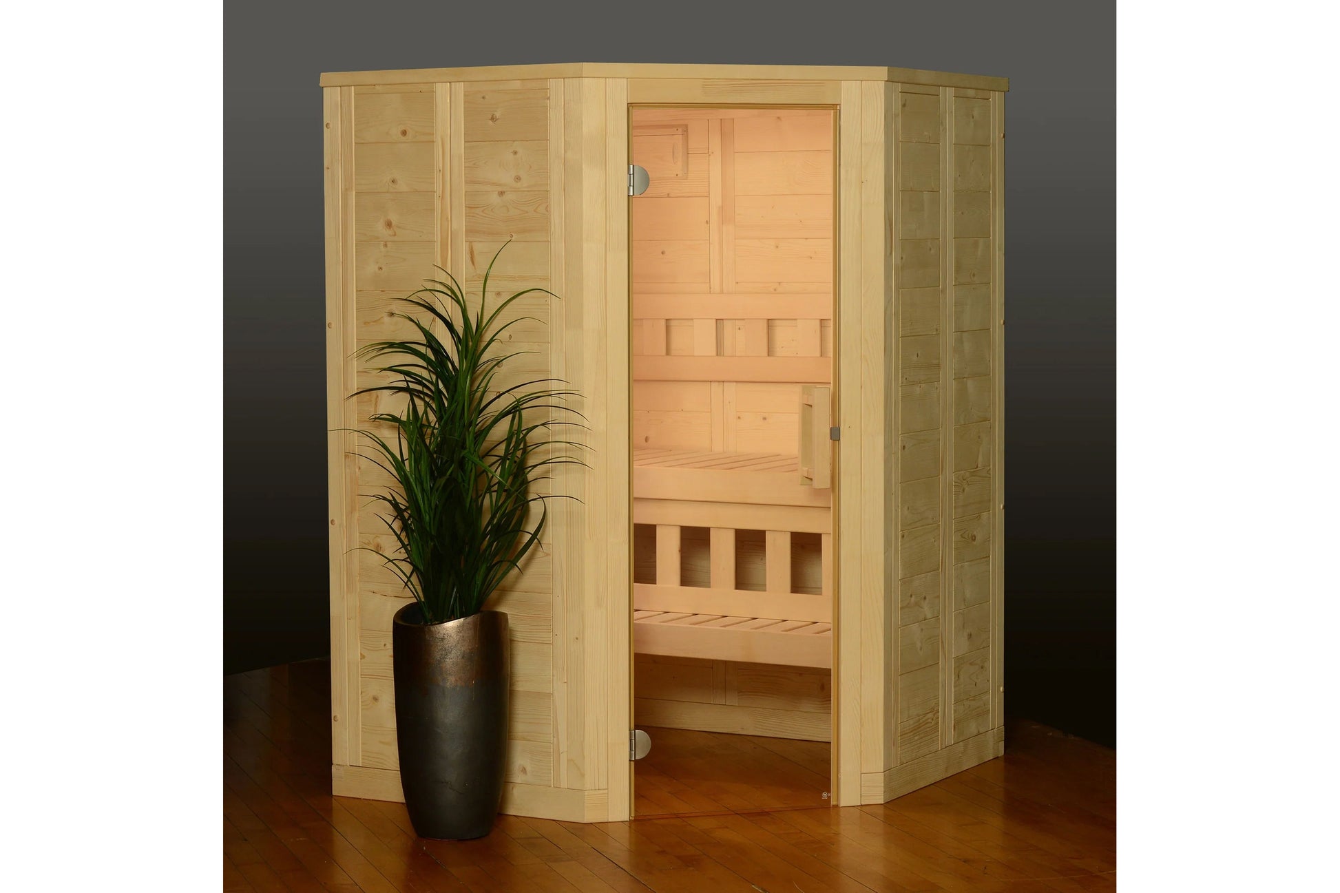 Natural wood corner sauna with light pine construction, glass door, interior benches, and decorative plant on wooden floor
