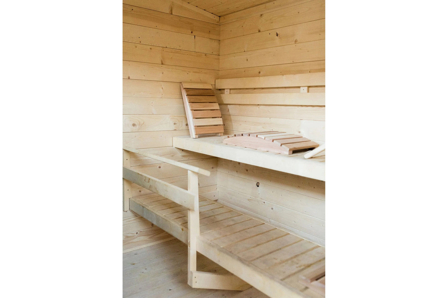 Interior view of wooden sauna with tiered bench seating, ladder, and light wood construction throughout