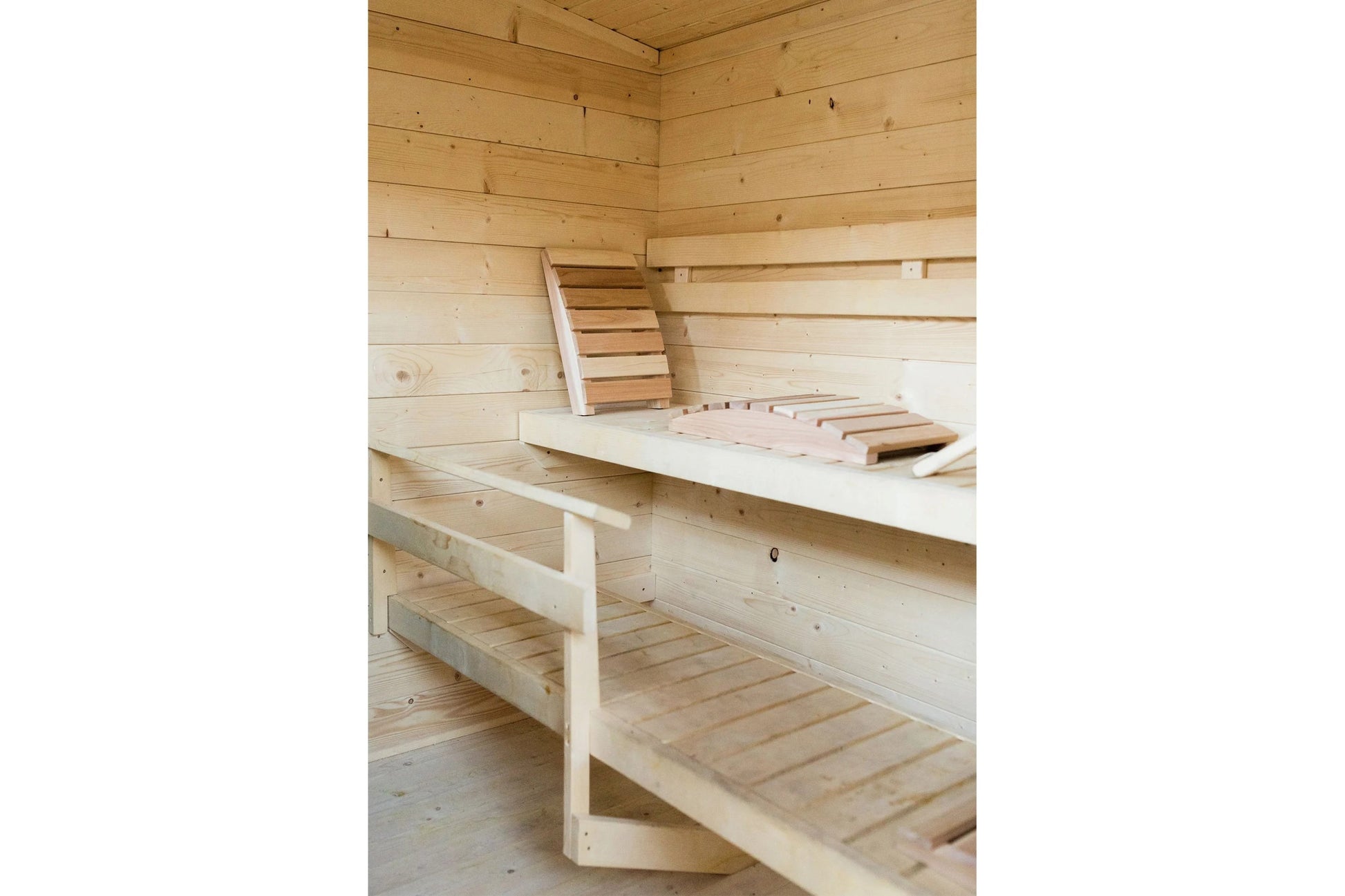Interior view of wooden sauna with tiered bench seating, ladder, and light wood construction throughout