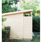 Cream-colored wooden sauna cabin with horizontal siding, louvered wall panel, and chimney pipe on roof, surrounded by green h