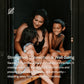 Woman and two children smiling together inside wooden sauna with black interior walls