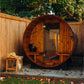 Barrel sauna with rounded wooden exterior, glass door, and wooden benches inside, situated in backyard garden setting with wo