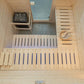 Interior overhead view of wooden sauna with pine walls, two benches with blue backrest supports, heater with gray stones, sky