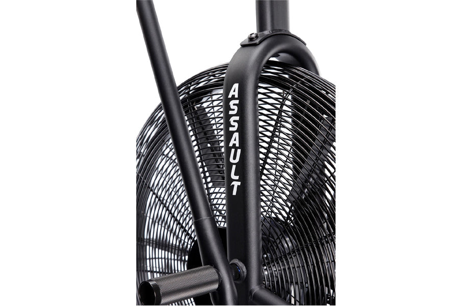 Black stationary assault bike with mesh fan wheel and "Assault" branding on frame, white background