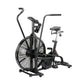 Black air bike with large fan wheel, dual handlebars, padded seat, and footrests on white background