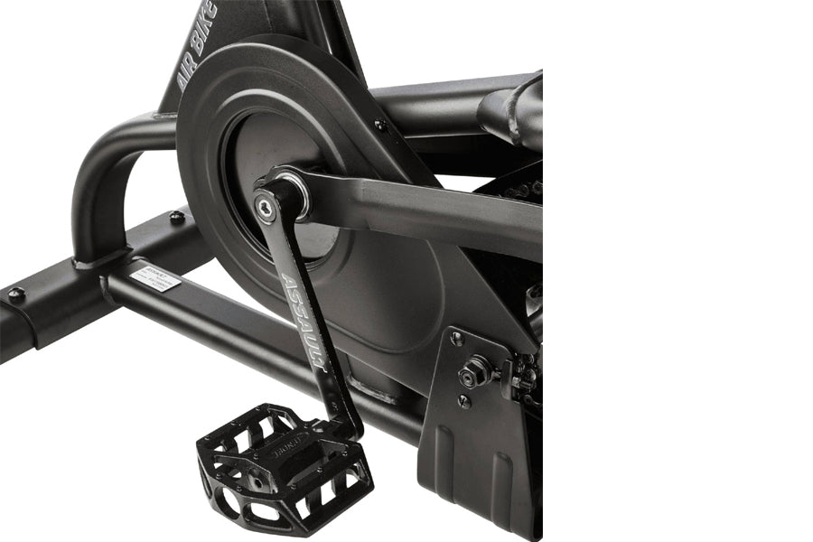Black exercise air bike with large fan wheel, handlebars, and foot pedals on white background
