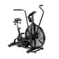 Black upright stationary air bike with large fan wheel, padded seat, dual handlebars, and digital display on white background