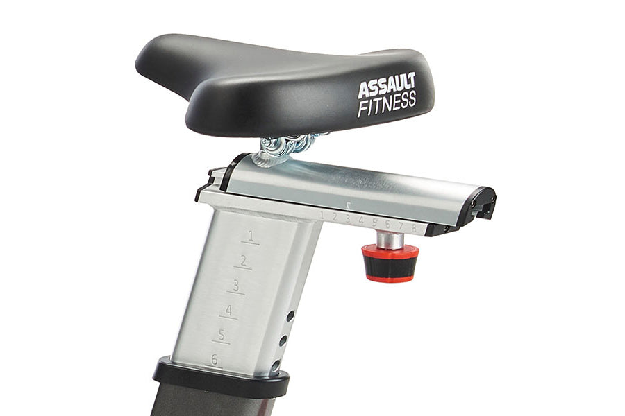 Assault Fitness exercise bike seat and handlebars detail with resistance adjustment knob on white background