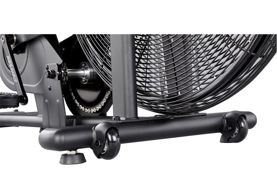 Black stationary air bike with dual fan wheels, metal frame, and rolling casters, detail view of base and mechanical componen