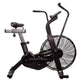 Black stationary air bike with large fan wheel, curved handlebars, and padded seat on white background