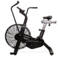 Black and gray stationary air bike with large fan wheel, curved handlebars, and padded seat on white background