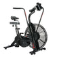 Black stationary air bike with large fan wheel, padded seat, dual handlebars with phone holder, and resistance adjustment on 