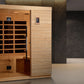 Cedar wood infrared sauna with glass door, golden heat elements, digital control panel, and bench seating in modern showroom 
