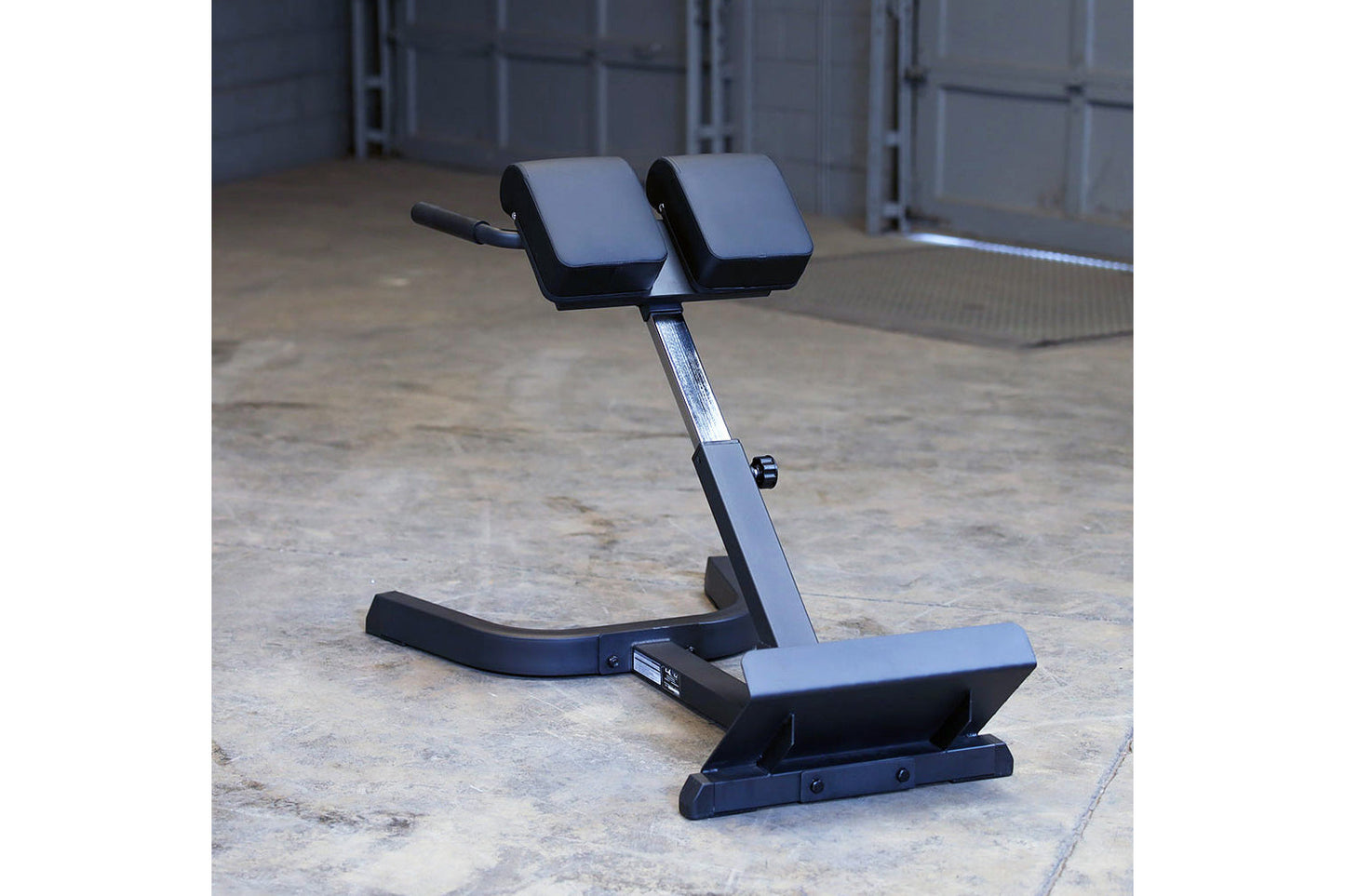 Body-Solid hyperextension machine with dual padded foot rests and adjustable back support on concrete floor
