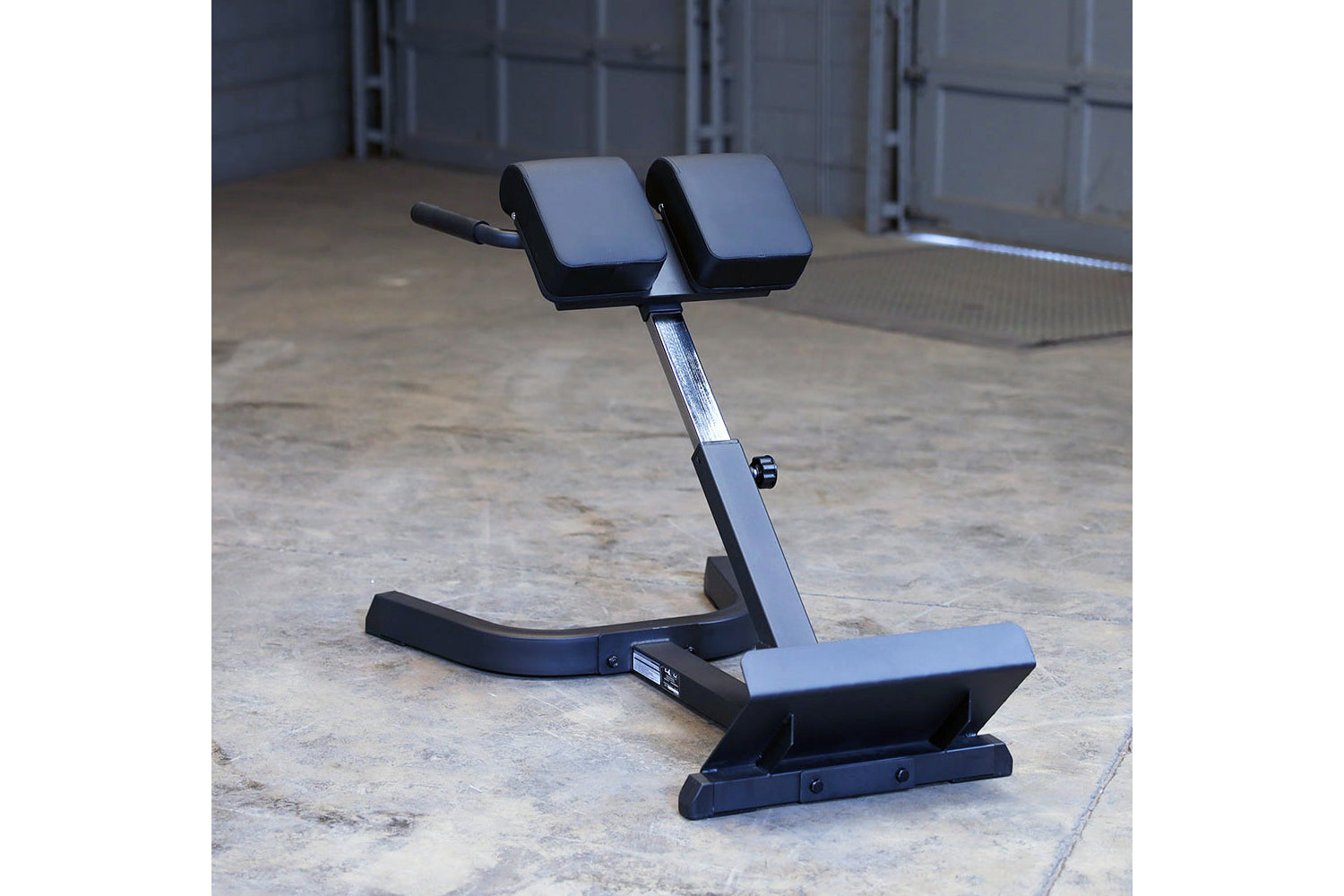 Body-Solid hyperextension machine with dual padded foot rests and adjustable back support on concrete floor