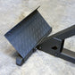 Black textured footplate attached to metal hyperextension machine frame on concrete surface