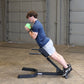 Man performing abdominal exercise on black Body-Solid hyperextension bench, holding green medicine ball, wearing navy t-shirt