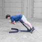 Man performing ab exercise on black hyperextension bench holding green medicine ball in garage setting