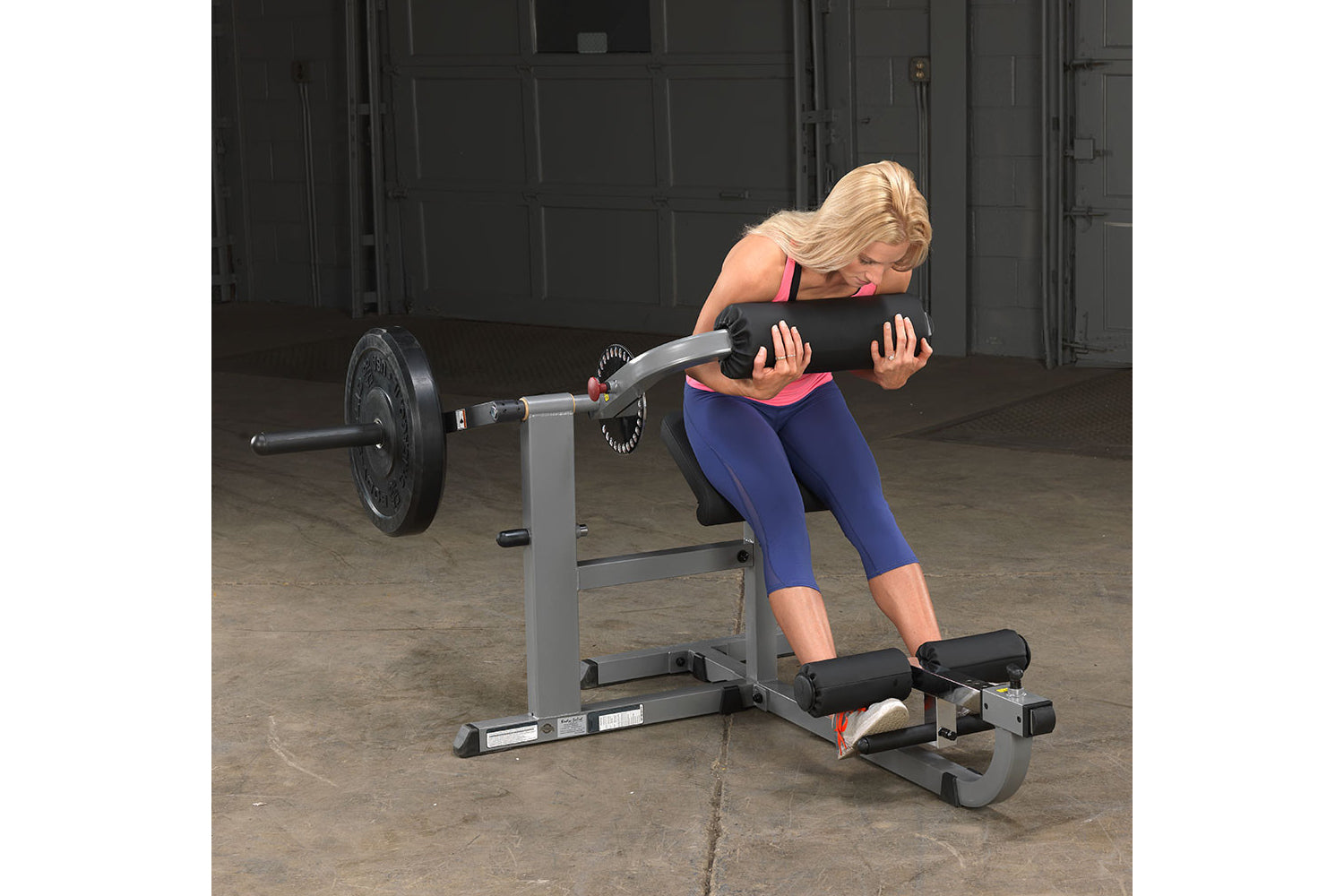 Woman performing ab exercise on gray and black Body-Solid Ab & Back Machine with weighted barbell in gym setting