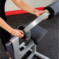 Person using silver and black ab and back machine with padded seat and handles in gym setting
