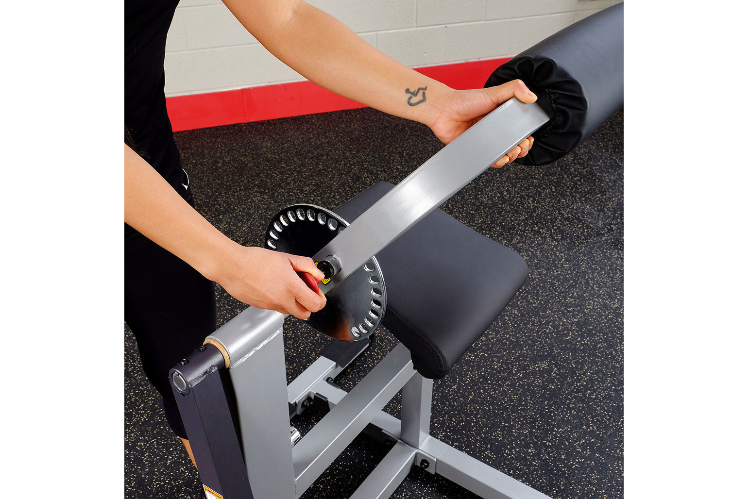Person using silver and black ab and back machine with padded seat and handles in gym setting