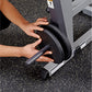 Hand gripping black padded handle of Body-Solid Ab & Back Machine on speckled gym floor