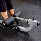 Person in black leggings using gray and black ab and back exercise machine on speckled gym floor