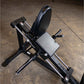 Black compact leg press machine with gray padded seat and backrest, chrome foot plate, on concrete floor