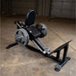 Black and silver leg press machine with padded seat back, weight plate pegs, and footplate on concrete garage floor