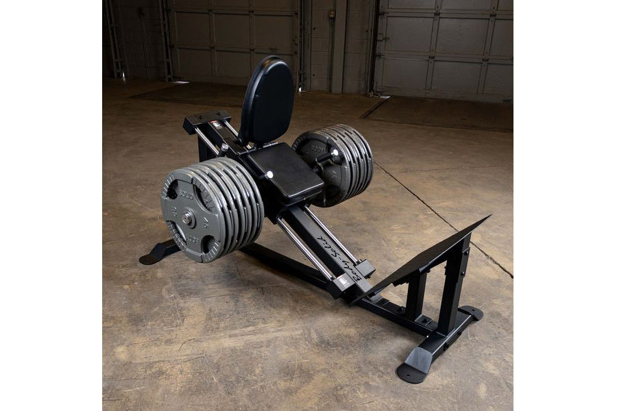 Black leg press machine with padded seat and backrest, dual metal weight plate holders, on concrete gym floor
