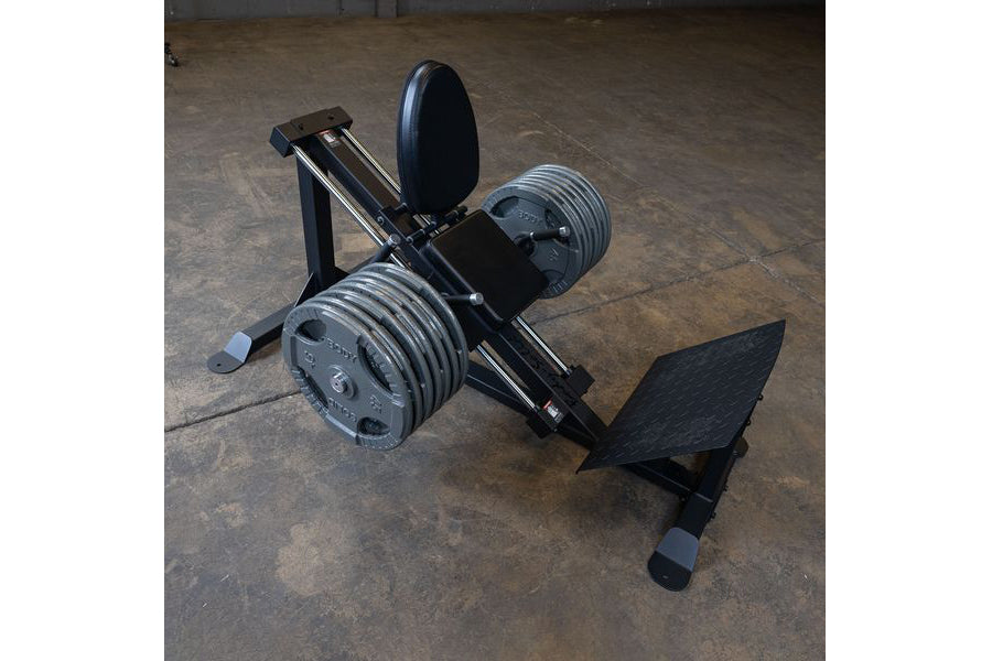 Body-Solid black compact leg press and hack squat machine with weight plates and adjustable seat on concrete floor