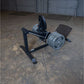 Black compact leg press and hack squat machine with chrome weight plates on concrete garage floor