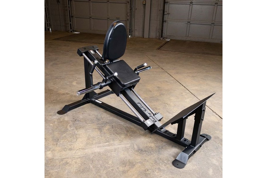 Black leg press and hack squat machine with padded seat and backrest, displayed in garage setting