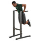 Man in green shirt performing dips on black and gray Body-Solid Dip Station against white background