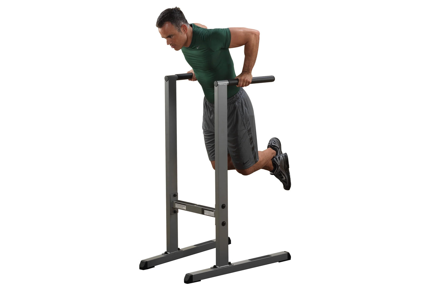 Man in green shirt performing dips on black and gray Body-Solid Dip Station against white background