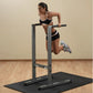 Woman using gray and black dip station with pull-up bar on exercise mat, wearing black sports bra and shorts with white trim