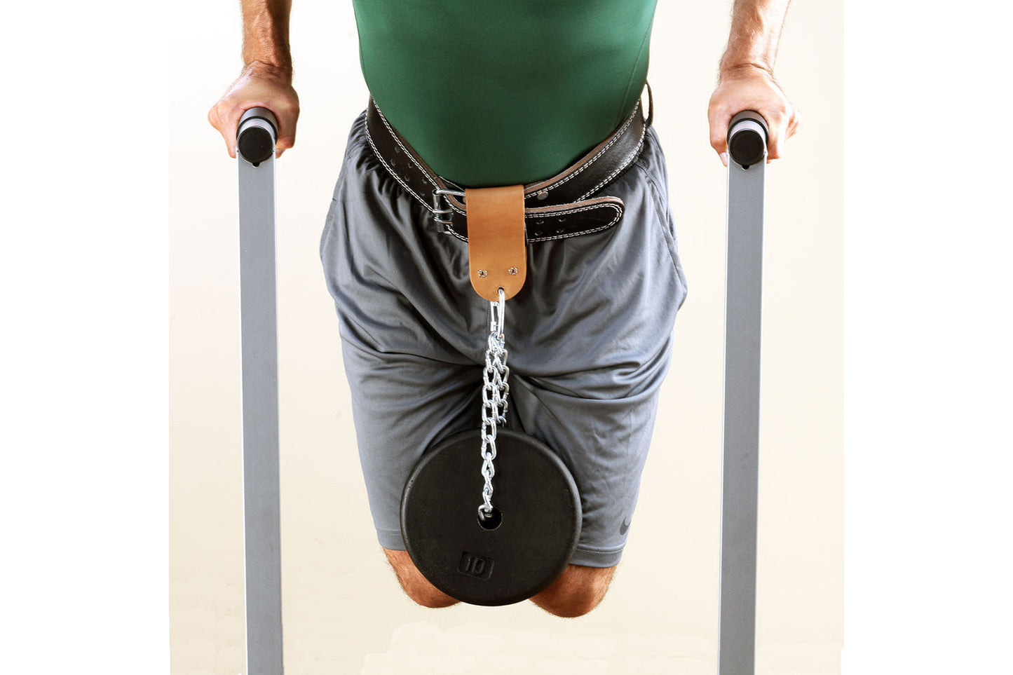 Man wearing green tank top and gray shorts using dip station with black weight plate attached, holding parallel bars on white