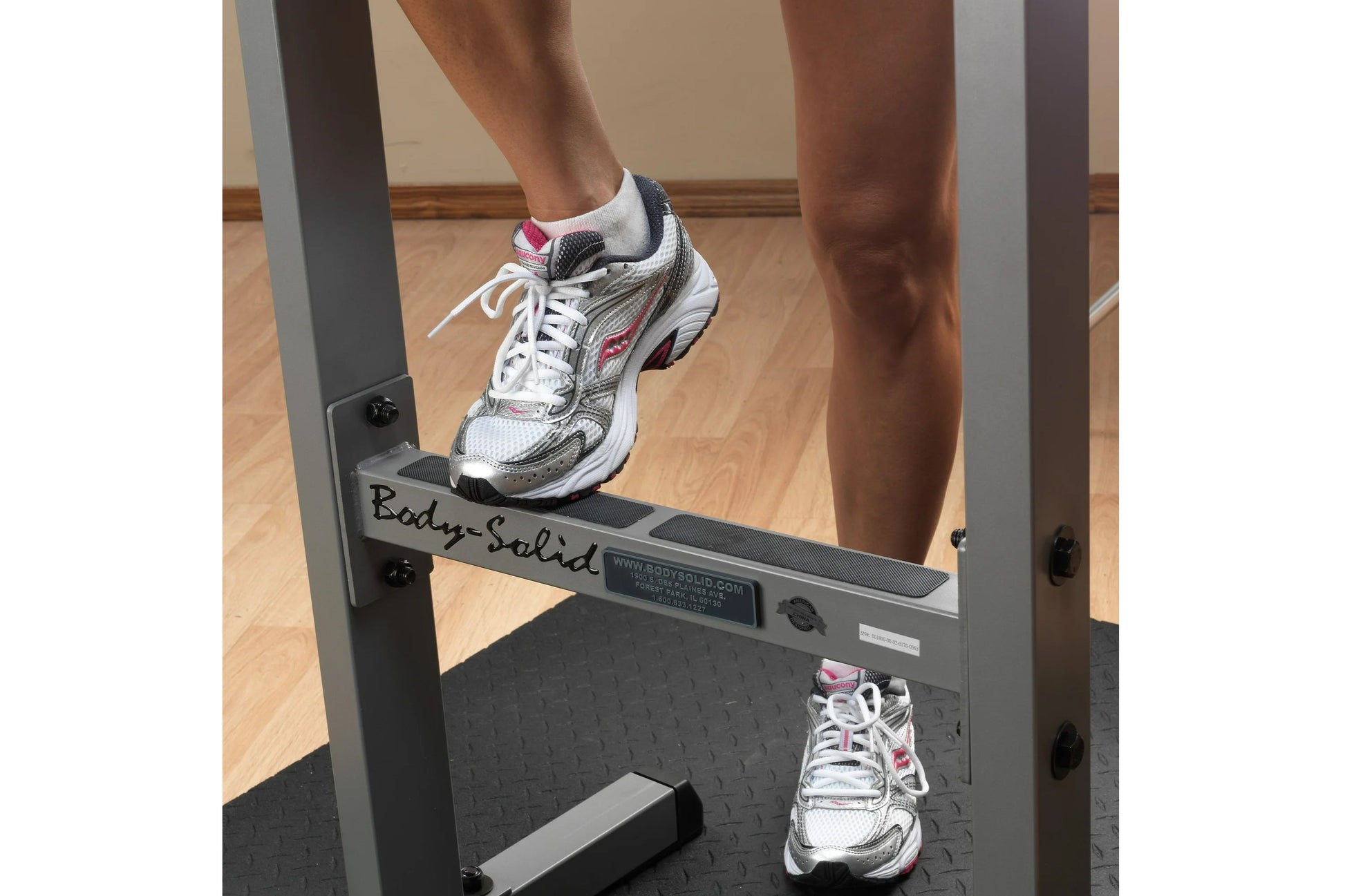 White, gray and pink mesh running shoe with white laces worn by model on Body-Solid dip station, shown in gym setting
