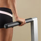 Person gripping black cylindrical pull-up bar with white and silver frame, wearing black shorts with white stripe