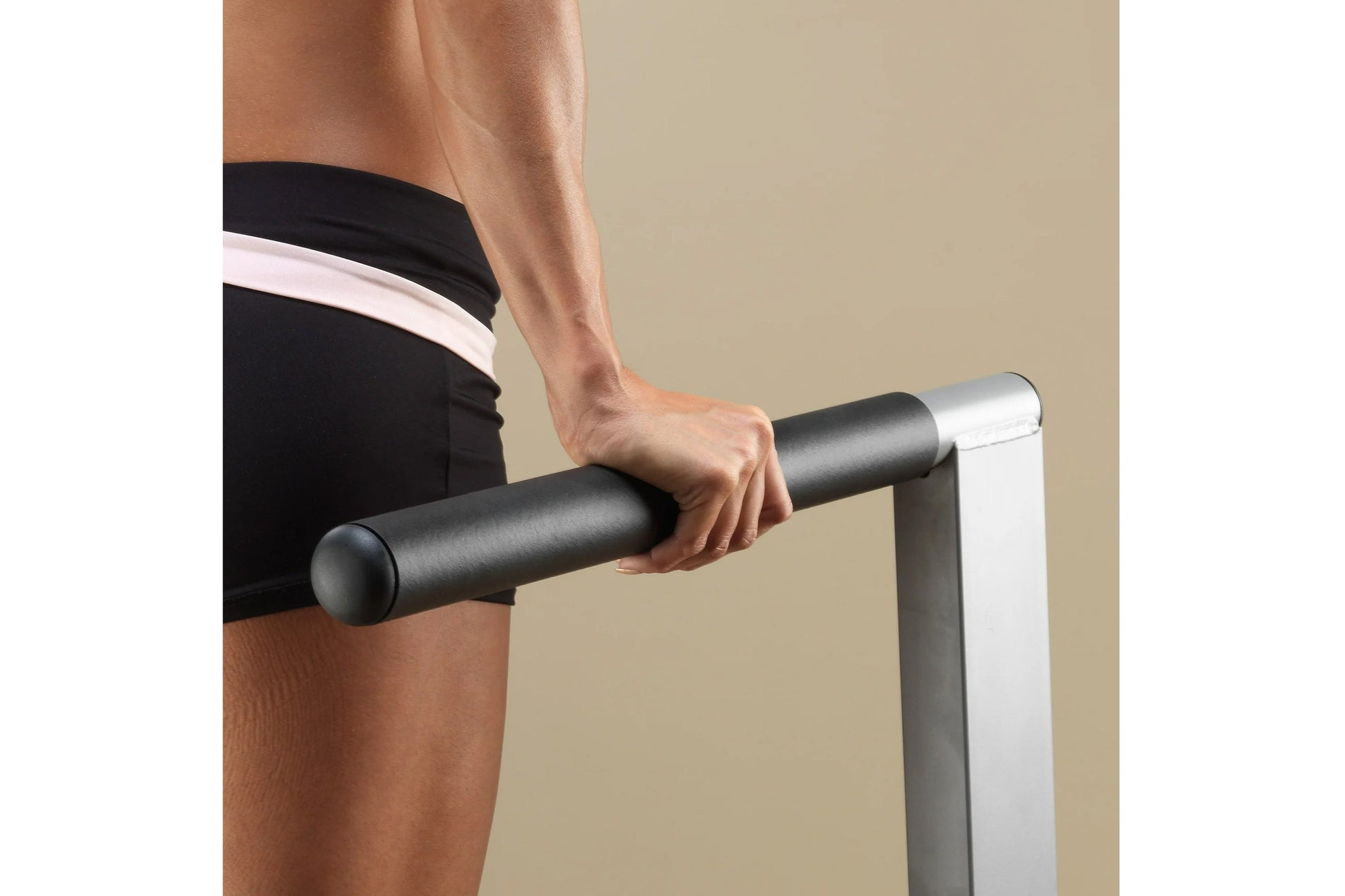 Person gripping black cylindrical pull-up bar with white and silver frame, wearing black shorts with white stripe